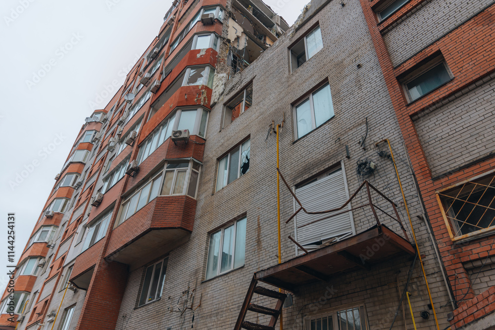 Fototapeta premium Russian missile hits residential building in Dnipro, Ukraine. Aftermath of enemy attack on city. Destroyed residential multi-story building. Close-up. War. Aftermath of explosion.
