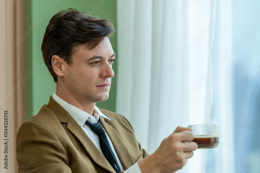 pensive man in suit holding coffee cup looking out window pensive man in suit holding coffee cup looking out window