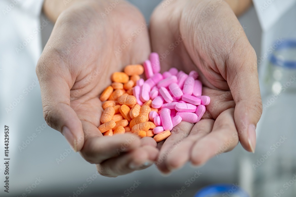 A close up of a handful of pink and orange pills in someone's hand A close up of a handful of pink and orange pills in someone's hand