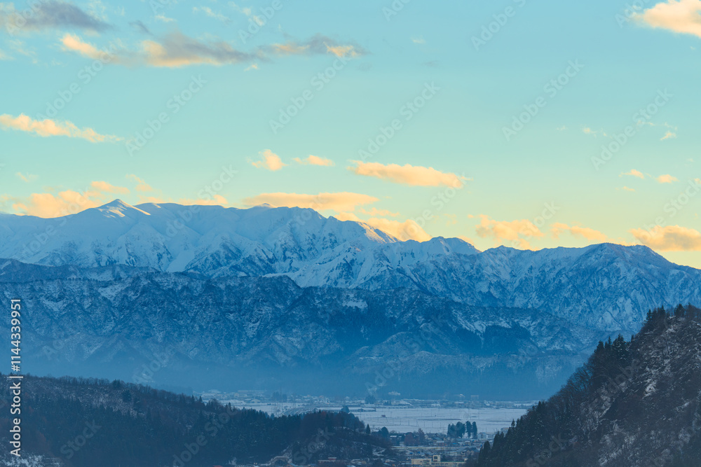 朝もやに浮かぶ雪山と朝焼け