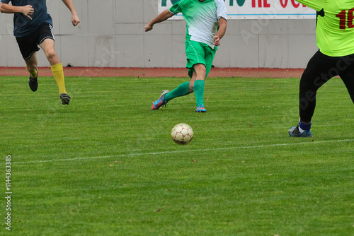 A strike by an attacking soccer player past the goalkeeper and defender, footballers in green and blue uniforms, dynamic photograph of footballers in motion on the football field, close-up. photo