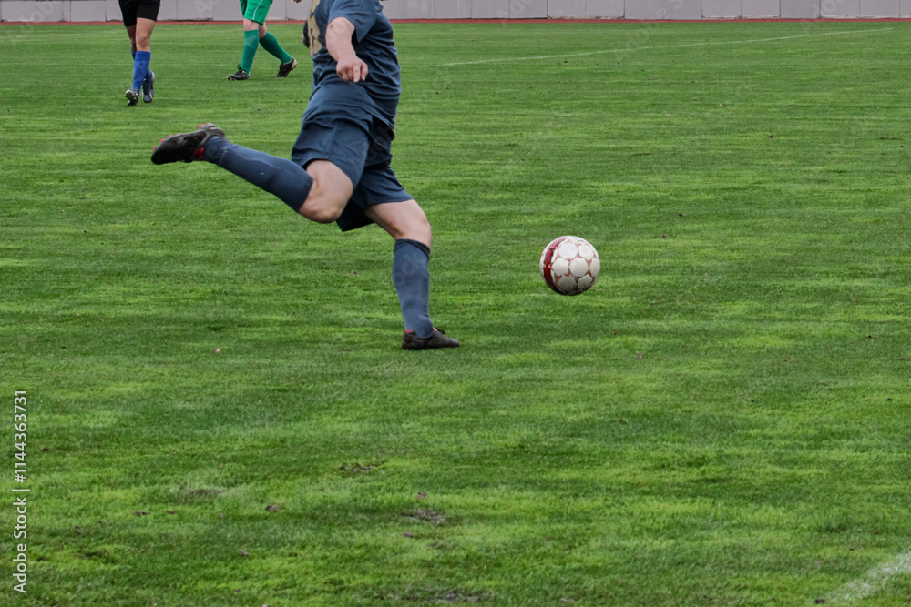 One attacking soccer player in blue uniform prepares to kick the ball, game tactics in football, footballer with the ball on the green football field close-up. One attacking soccer player in blue uniform prepares to kick the ball, game tactics in football, footballer with the ball on the green football field close-up.