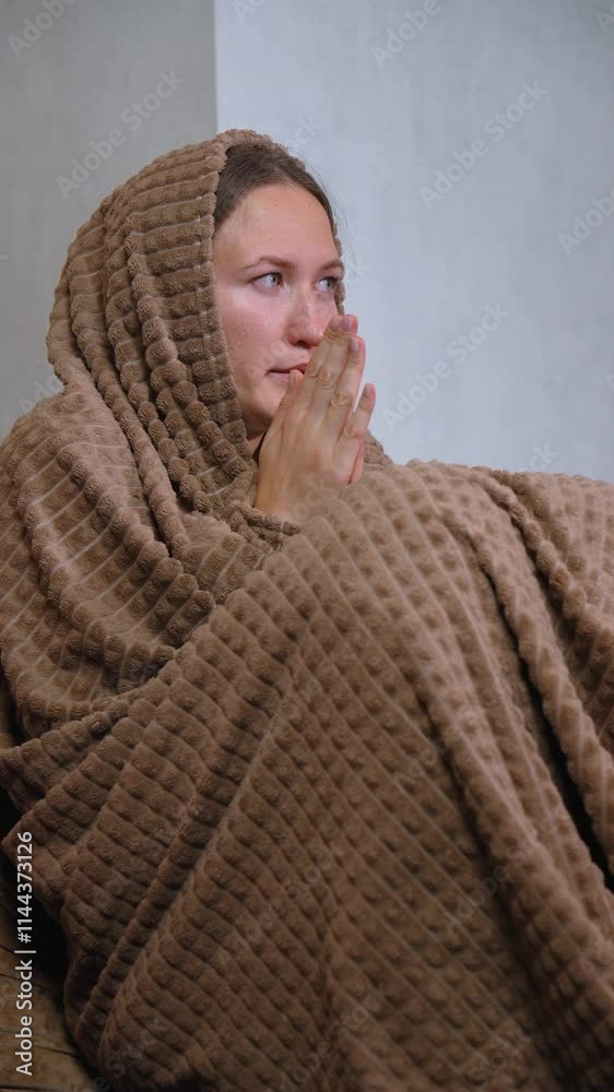 Woman wrapped in knitted blanket sits alone, shivering from cold, on sofa in unheated apartment without central heating due to debt. feels uncomfortable when trying to warm up indoors Woman wrapped in knitted blanket sits alone, shivering from cold, on sofa in unheated apartment without central heating due to debt. feels uncomfortable when trying to warm up indoors