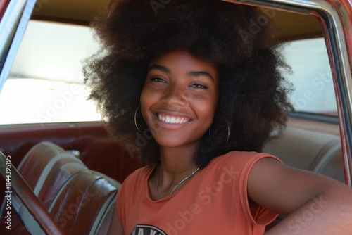 Smiling african female teen in vintage car interior with natural hair Teen Driving Awareness Month photo