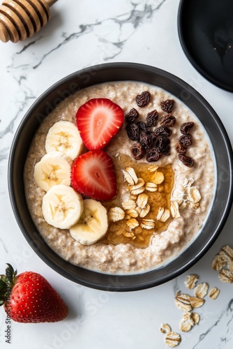 Delicious bowl of oatmeal topped with fresh fruit, honey, and nuts in a styli...