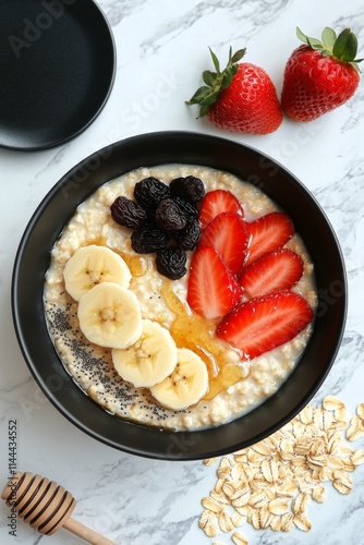 Delicious bowl of oatmeal topped with fresh fruit, honey, and nuts in a styli...