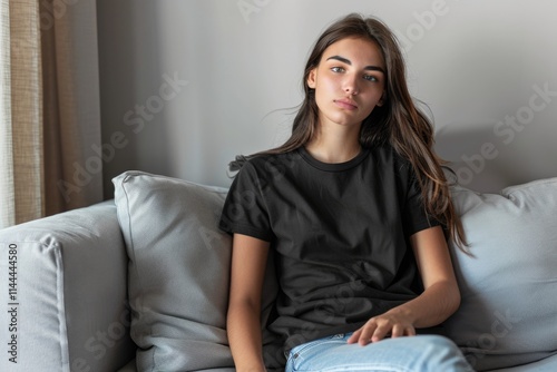 Young latin woman sitting on the sofa wearing a black product mock up t shirt with copy space design photo