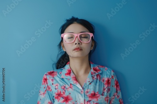 Woman in a pink floral shirt is wearing pink glasses and appears to be sleeping. Concept of relaxation and comfort, as the woman is in a cozy and peaceful setting