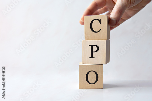 Female hand holding wooden cube with CPO letters on white background. photo