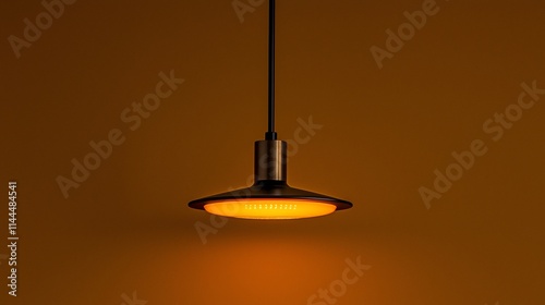 Modern minimalist pendant lamp emitting warm light against a brown wall.