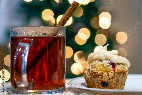 Christmas mulled cider and spices next to a homemade Blueberry Muffin or cupcake on a Christmas holiday background.