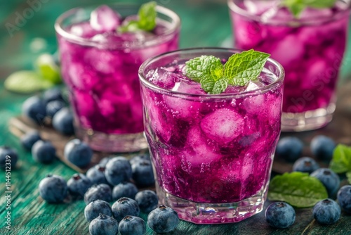 Refreshing blueberry mint drink served in glasses with ice and fresh mint lea...