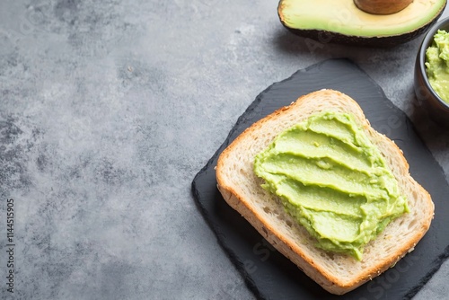 Flat Lay of Avocado Spread on Bread with Half Avocado on Gray Background photo