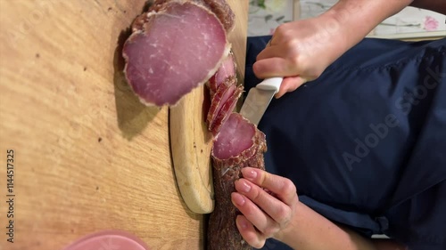 A woman is cutting pieces of dried pork. She makes a loin, dried pork tenderloin, processing pork at home. Vertical video. Close-up