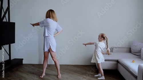 Caucasian family mother and daughter performing workout at home health and fitness. Young adult mother and little daughter doing workout regular physical activity fosters strong family connections.