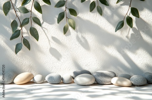Arrangement of smooth stones and green leaves creating a serene composition o...