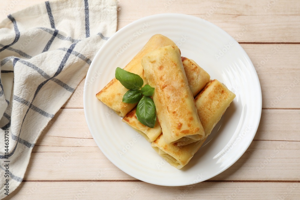 Delicious rolled crepes with basil on wooden table, top view Delicious rolled crepes with basil on wooden table, top view