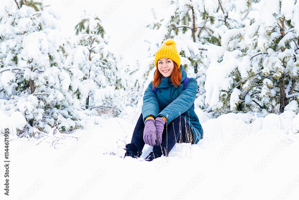 A cheerful woman in a yellow hat and gloves enjoying a snowy day