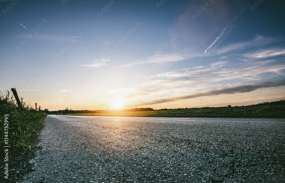 Empty long mountain road to the horizon on a sunny summer day at bright sunset
