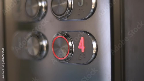 Unrecognized man pressing button of elevator with the polished metal surface. An elevator panel lights up while ascending to the fourth floor. Modern hotel concept.