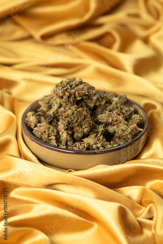 in a white young female hand a dry bud of medical marijuana. On a festive golden background
