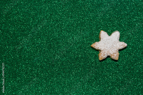 One Christmas star cookie sprinkled with powdered sugar creates a festive winter mood on a bright green shiny background. photo