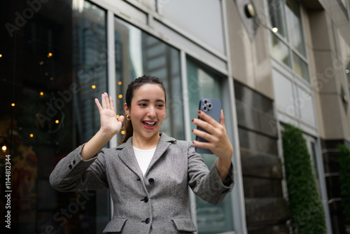Принти на полотні Smiling businesswoman waving at her smartphone while engaging in a video call ou