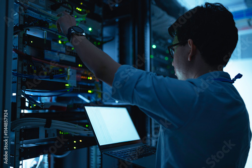 Computer engineer is setting up network in server room,Systems Maintenance Technician,Male engineer working in server room at modern data center photo