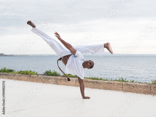 Skilled brazilian male practitioner in action demonstrating traditional capoeira by the seaside