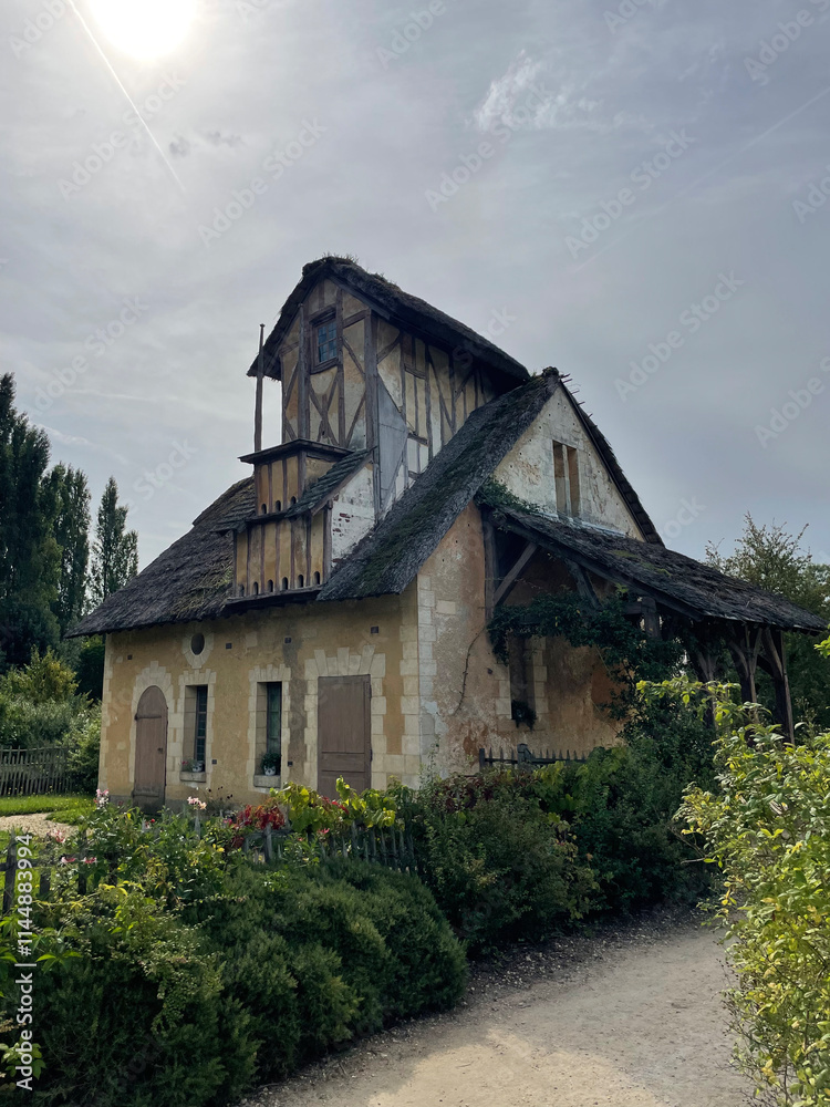 Fototapeta premium The Queen's Hamlet at the Trianon in Versailles, featuring charming rustic cottages, lush greenery, and a tranquil lake, embodying pastoral elegance and historic charm