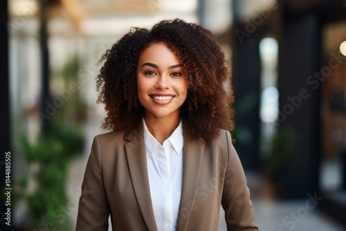 Young smiling businesswoman posing in modern office building corridor