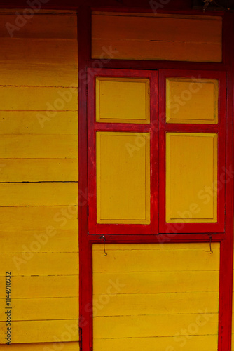 Bright yellow wall with red window frames, showcasing vibrant colors and textures