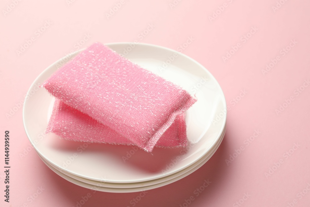 Sponges and stack of plates on pink background, closeup Sponges and stack of plates on pink background, closeup