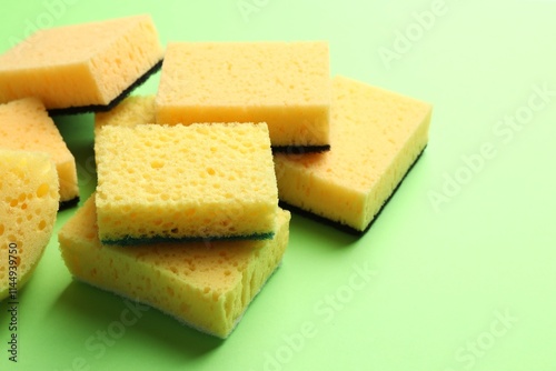 Pile of sponges on green background, closeup. Space for text