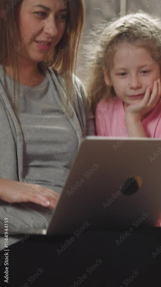 Woman shows little children funny videos on modern laptop. Toddler and preschooler look at screen of device on lap of mom in wheelchair closeup Woman shows little children funny videos on modern laptop. Toddler and preschooler look at screen of device on lap of mom in wheelchair closeup