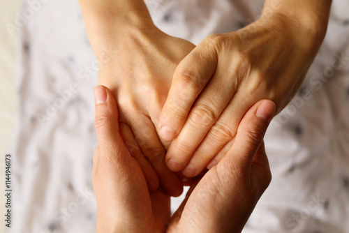 Two hands gently hold each other, conveying tenderness and warmth in a moment of connection. The soft background suggests a calm atmosphere, enhancing the intimate exchange