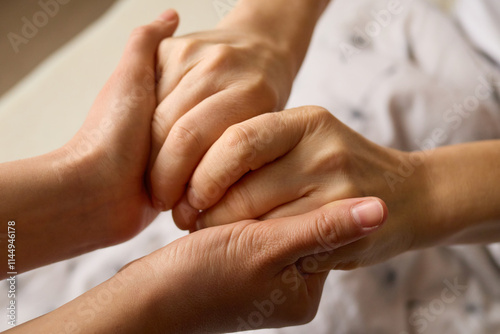 Two hands intertwine in a gesture of solidarity, symbolizing support and care. The setting conveys a sense of intimacy and reassurance between individuals