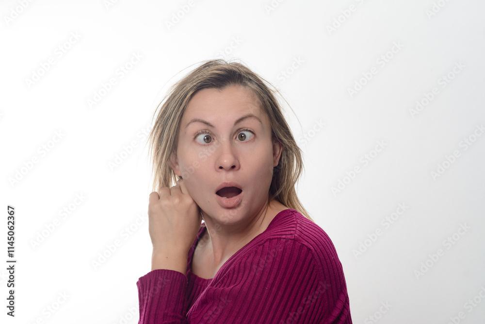 A woman with a surprised facial expression, her eyes crossed, glances to the side against a white background. She touches her face with her hand, adding to her look of astonishment. A woman with a surprised facial expression, her eyes crossed, glances to the side against a white background. She touches her face with her hand, adding to her look of astonishment.