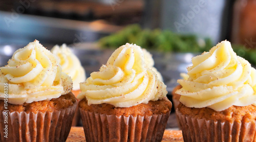 Baking carrot cupcakes with fresh carrots, spices, flour, sugar and eggs.  Spiced carrot cupcakes with cream cheese frosting ready for the bake shop.