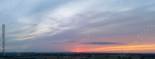 A breathtaking sunset over the horizon, showcasing vibrant colors blending into the clouds, creating a serene atmosphere in nature.