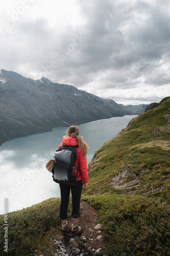 Woman Hiking Along Norwegian Fjord Surrounded by Majestic Mountains and Water photo