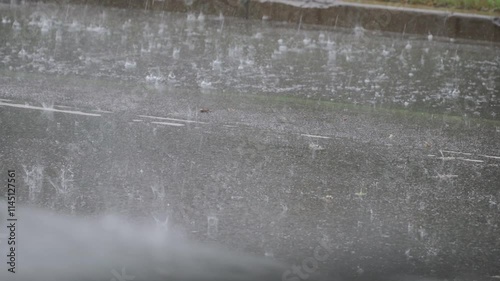 Surface of asphalt road covered with water with traces of falling raindrops during heavy rain in city. Background video of bad weather and flowing streams of water on city street.