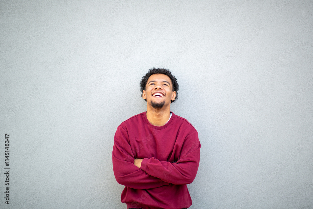 Man in red sweater smiling with arms crossed looking up Man in red sweater smiling with arms crossed looking up