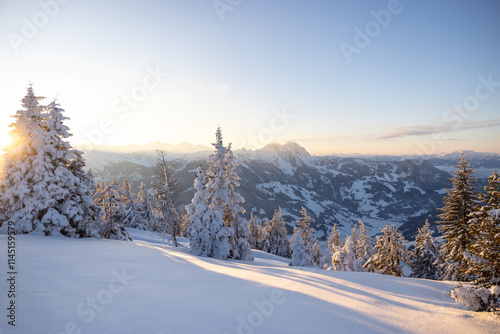 Winter sunset in the Alps. Golden light on the mountain range and a cold wilderness foreground.