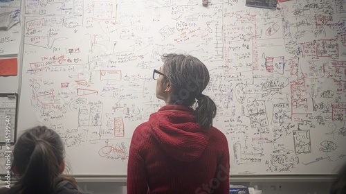 Two individuals analyzing a complex whiteboard filled with notes and diagrams.