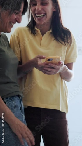 Mother and daughter sharing fun moments using smartphone. Hispanic, single family