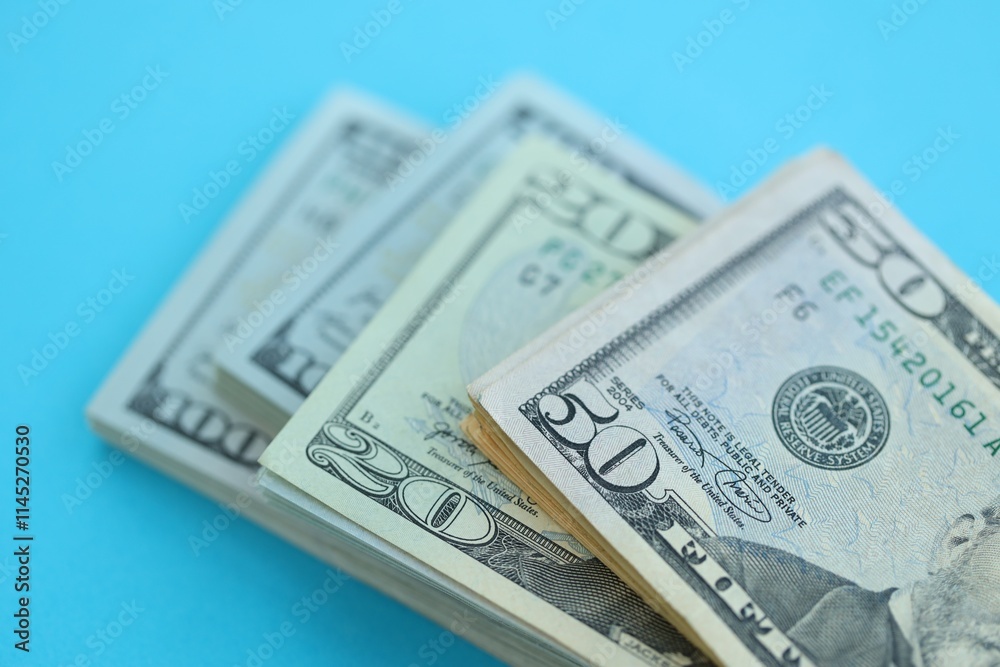 Big amount of hundred, fifty and twenty dollar bills in thick stack lies on bright blue color paper background Big amount of hundred, fifty and twenty dollar bills in thick stack lies on bright blue color paper background