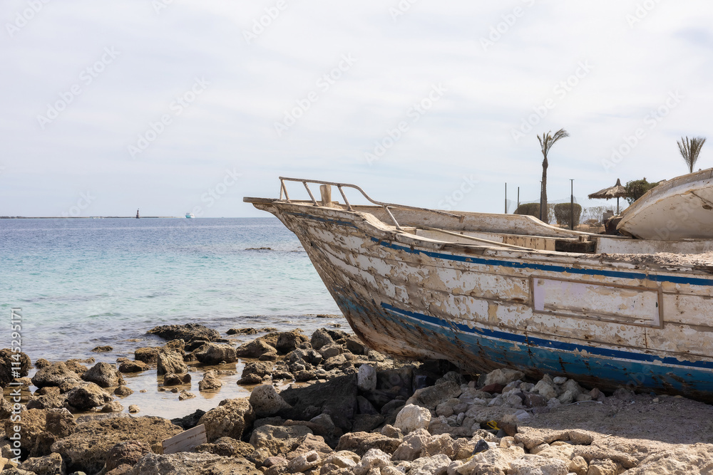 Weathered boat on rocky shore by a calm sea, evoking tranquility and nostalgia Weathered boat on rocky shore by a calm sea, evoking tranquility and nostalgia