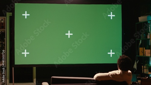 Foto Man zapping through green screen TV channels using remote, relaxing on couch in living room used as home theatre