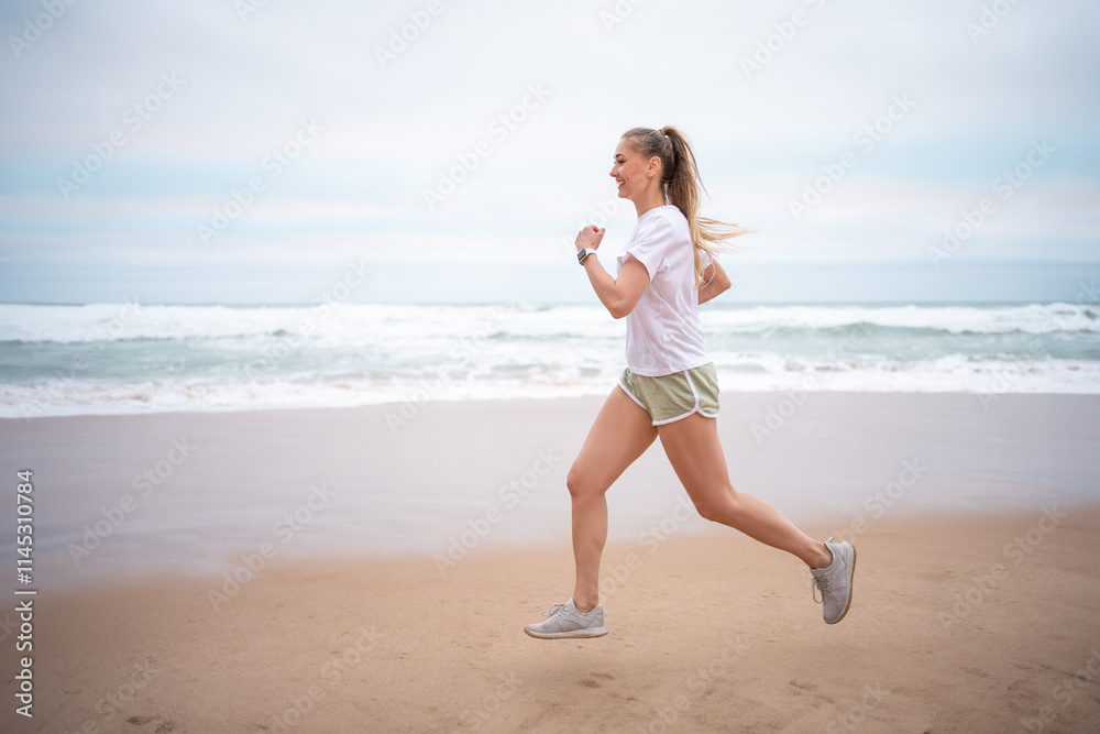 Happy sporty woman jogging on wet seashore against sky at beach. Full body side view of smiling female looking away while exercising during daytime. Happy sporty woman jogging on wet seashore against sky at beach. Full body side view of smiling female looking away while exercising during daytime.